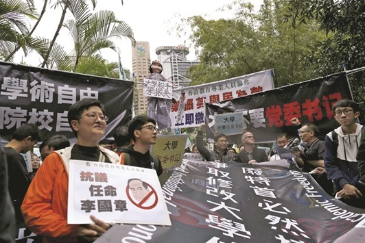 Demonstrators hold up signs to protest against the appointment of a pro-Beijing professor as the chairman of the governing council of the University of Hong Kong, in Hong Kong yesterday. The sign (left) reads u201dAgainst the appointment of Arthur Liu201d.