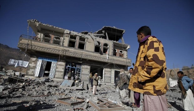 People look at a damaged building at the site of a Saudi-led air strike in Sanaa on Monday.