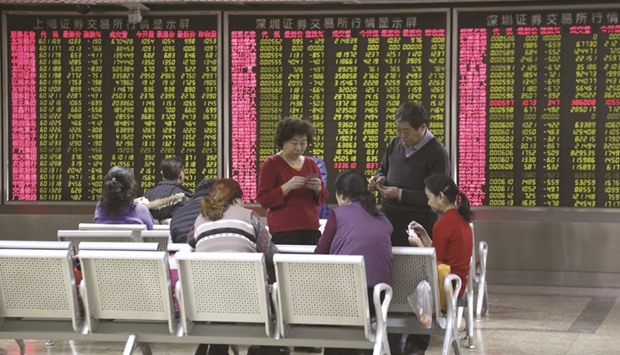 Investors play cards in front of an electronic board showing stock information at a brokerage house in Beijing. Chinau2019s benchmark CSI300 share index tumbled 7% on the first session of 2016 yesterday, prompting the stock exchange to halt trading for the rest of the day.