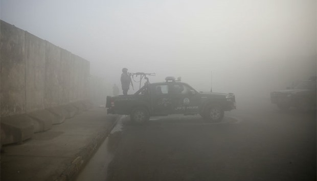An Afghan policeman keeps watch atop a police vehicle near the site of Monday's blast near the Kabul international airport, during a foggy morning. Reuters
