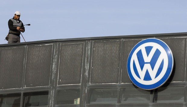 A worker stands next to a Volkswagen logo at a dealership in Madrid. Although US lawsuits are typically settled at a fraction of the theoretical maximum penalty, analysts say Volkswagen (VW) could face a larger bill than previously anticipated.