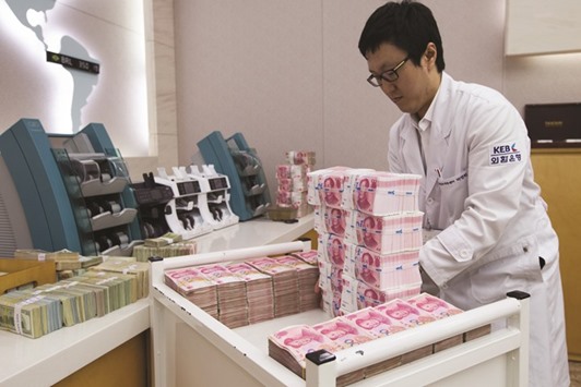 An employee arranges Chinese one-hundred yuan banknotes at the Korea Exchange Bank headquarters in Seoul. The offshore yuan dropped beyond 6.70 per dollar for the first time since September 2010, about two months after trading was first permitted in Hong Kong, while the onshore rate was 6.5560 in Shanghai.