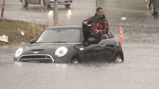 A driver climbs out of a window of his car after driving onto a flooded road in Van Nuys, California.