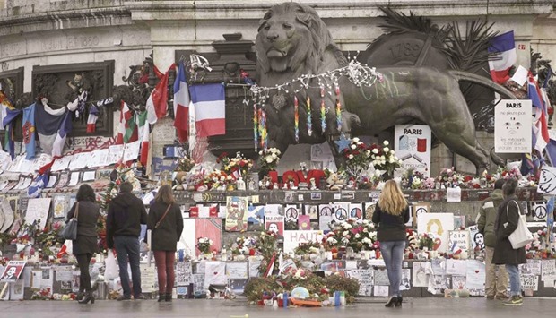 People look at flowers and messages to pay tribute to the victims of last yearu2019s January and November shooting attacks near the statue at the Place de la Republique in Paris.