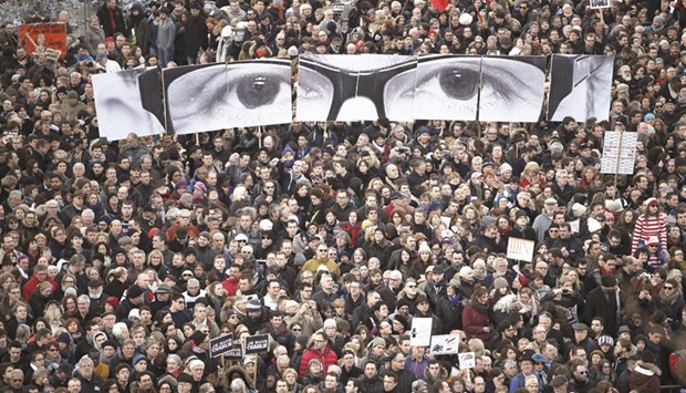 This January 11, 2015 picture shows people hold panels to create an image depicting the eyes of late Charlie Hebdo editor Stephane Charbonnier, known as u2018Charbu2019, as hundreds of thousands of French citizens take part in a solidarity march (Marche Republicaine) in the streets of Paris.