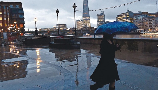 A pedestrian walks alongside the River Thames in front of the Shard skyscraper in London. Britainu2019s Chancellor of the Exchequer George Osborne has identified the slowing economies of China, Brazil and Russia, the slide in commodity prices and escalating political tensions in the Middle East as potential hazards for the UK.