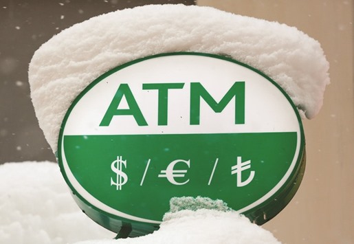 Turkish lira and other currency symbols are seen over a snow-covered ATM of a bank in central Istanbul yesterday. The lira, which has lost around 20% in value against the dollar over the last three months, had slumped to a new low on Monday as political uncertainty in the country took its toll.