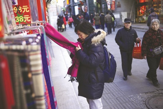 A woman selects a scarf at the entrance to a store along a street in Beijing. Chinau2019s producer prices rose at their swiftest pace in more than five years in December, the government said yesterday.
