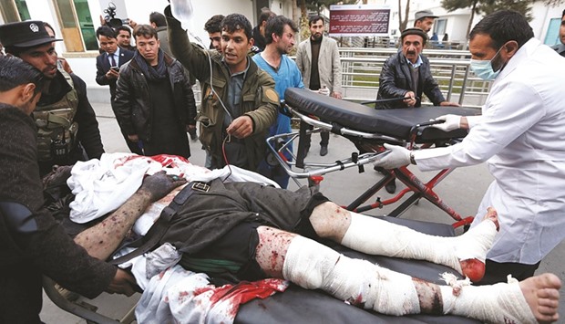 Men carry an injured policeman to a hospital after a suicide attack in Kabul yesterday.