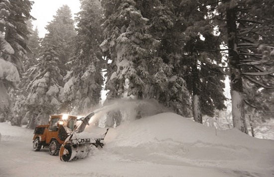 A private contractor clears deep snow from a driveway during a heavy winter storm in Incline Village, Nevada.
