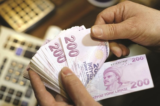 A money changer counts Turkish lira bills at a currency exchange office in Istanbul. The currency has dropped 8.6% against the dollar in the yearu2019s first eight trading days, adding to last yearu2019s 17% slump. Itu2019s set a new record on six of them.