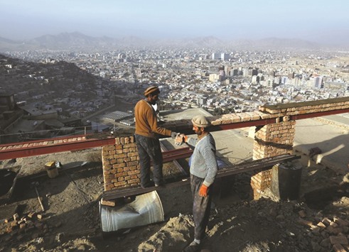 Afghan men build a house on a hilltop overlooking Kabul.