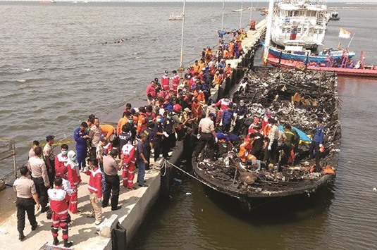 Rescuers search the charred passenger boat which was ferrying around 100 people off the coast of Jakarta to Tidung island, 50km from the capital. At least 23 people have been killed and 17 are missing after the boat caught fire near Jakarta.