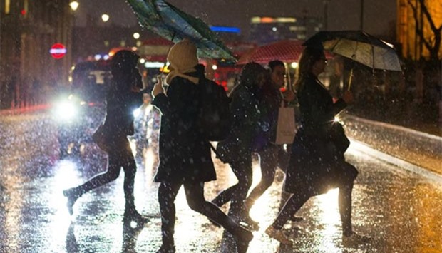 Pedestrians walk in heavy rain near the Houses of Parliament in central London on Thursday.