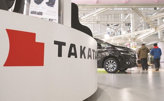 The logo of Takata is displayed at a car showroom in Tokyo. Shares in struggling auto parts maker surged yesterday following a report the company and US authorities could announce a settlement later in the day over deadly exploding airbags.