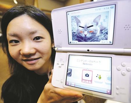 A girl displaying Japanese video game giant Nintendou2019s new portable video game console u2018DS LLu2019 at a press conference in Tokyo. Nintendo pulled the covers off its next-generation Switch games console yesterday as the company behind Pokemon and Super Mario tries to score big in the 21st century.