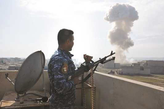 A member of the Iraqi security forces stands atop a building and watches the smoke billow, after his comrades detonated a booby-trapped car left behind by Islamic State (IS) group, in Mosulu2019s southern Sumer neighbourhood yesterday.