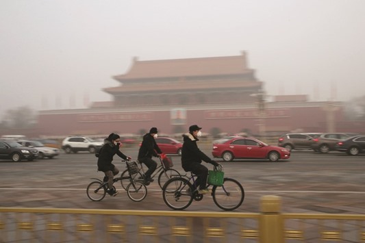 Cyclists wearing masks ride past Tiananmen Gate during a smog u2018red alertu2019 in Beijing last month.