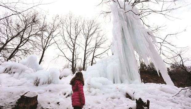 A woman stands yesterday in front of a frozen tree covered in water from a burst pipe near Librazhd in southeast Albania. Cold and icy weather has swept Albania over the last week causing several deaths, hundreds of fractures from slippages on icy roads, frozen water pipes and water tanks as well as left isolated many villages in the northeastern monotonous part of the small Mediterranean nation.