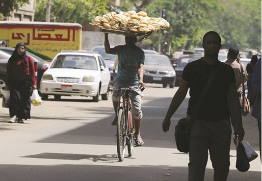 A bakery worker rides a bicycle as he carries fresh bread on his head in Cairo. The reforms come as Egypt faces major economic challenges after the political turmoil that followed the 2011 uprising.