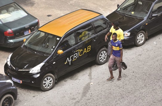 Two men walk past a taxi from the Africab company in Abidjan.