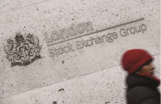 A woman walks past the London Stock Exchange building. FTSE 100 index was down 0.15% to 7,327.13 points at the closing bell yesterday.