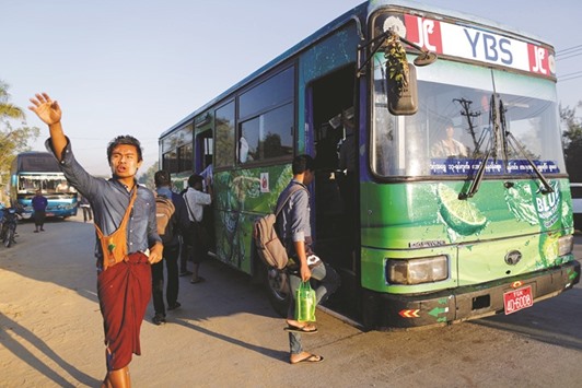 An assistant driver waves to passengers in Yangon, Myanmar.
