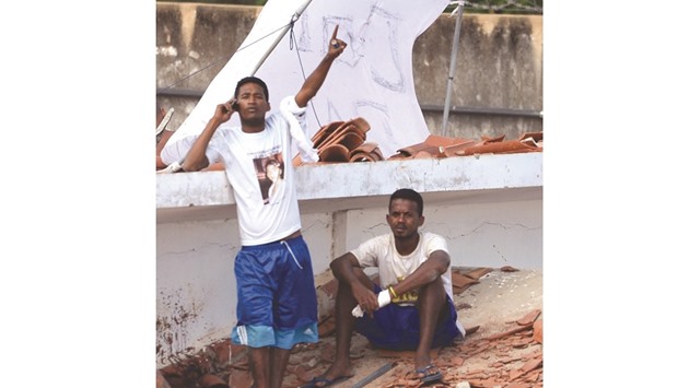 An inmate talks on his cellphone next to a prison mate on the roof of the Alcacuz Penitentiary Centre during a rebellion near Natal, Rio Grande do Norte state, northeastern Brazil, yesterday.