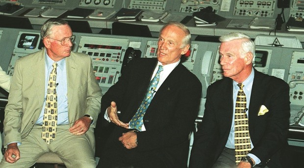 A July 16, 1999 photo of Apollo 11 Commander Neil Armstrong (left) and Apollo 17 Commander Gene Cernan (right) listen as Apollo 11 crewmember Edwin (Buzz) Aldrin answers questions from the media in a replica of the Apollo/Saturn 5 launch control room at Kennedy Space Center, Florida.