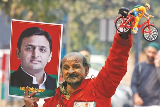 A Samajwadi Party worker holds a toy bicycle representing the partyu2019s symbol and a poster of Uttar Pradesh Chief Minister Akhilesh Yadav, following the Election Commissionu2019s decision to allot the bicycle symbol in Akhileshu2019s favour, outside the partyu2019s headquarters in Lucknow, yesterday.