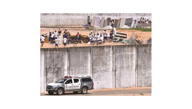 Police car drives past the wall of Alcacuz prison while inmates from different gangs protect themselves during an uprising, in Natal, Rio Grande do Norte state, Brazil, yesterday.