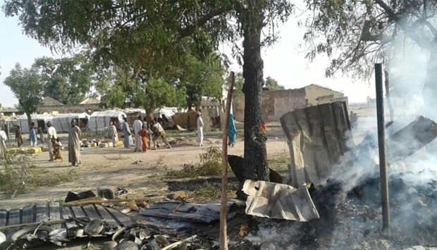 People walk at the site after a bombing attack of an internally displaced persons camp in Rann, Nigeria