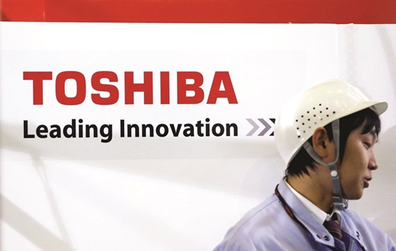 An employee stands next to a logo of Toshiba at the companyu2019s Yokohama complex, south of Tokyo. Battered by an accounting scandal in 2015, the firm was plunged back into crisis late last year after it emerged that it would have to write down cost overruns at projects handled by a US nuclear power plant construction firm which was recently acquired by its Westinghouse division.