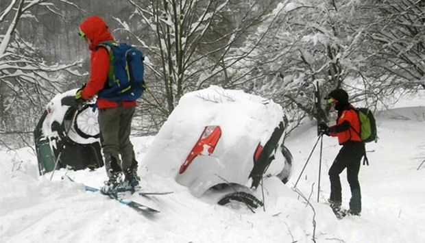 Members of Lazio's Alpine and Speleological Rescue Team are seen next to cars covered in snow in front of the Hotel Rigopiano in Farindola, central Italy, on Thursday.