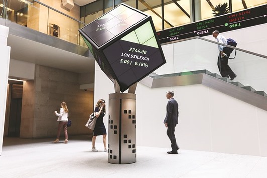 Visitors walk past an illuminated rotating cube displaying the share price information in the atrium of the London Stock Exchange Groupu2019s offices in London. LSE and Deutsche Boerse plan to keep their clearinghouses separate while allowing offsetting trades to cancel out, a process known as portfolio margining.