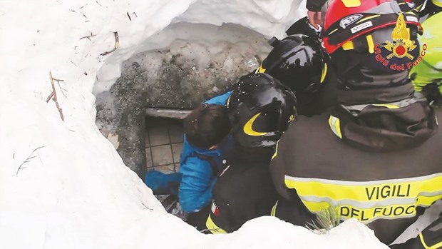A handout picture released yesterday shows a child (centre) being rescued from the Hotel Rigopiano.
