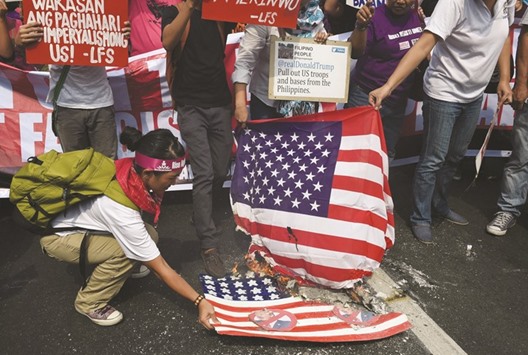 Activists burn a mock US flag (below) with President-elect Donald Trumpu2019s portrait and a real one (upper) during a rally in front of the US embassy in Manila yesterday.