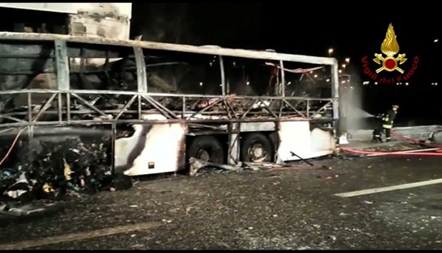 A still image taken from a video shows firefighters working next to a charred bus, which was carrying Hungarian students, on a side of a highway, near Verona, northern Italy.