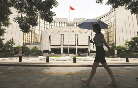 A woman walks past the headquarters of the Peopleu2019s Bank of China in Beijing. Commercial banks had 11tn yuan ($1.6tn) of sovereign and financial bonds outstanding as of December, a former PBoC official said yesterday.