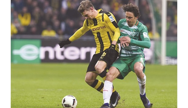 Bremensu2019s midfielder Thomas Delaney (R) and Dortmundu2019s Polish defender Lukasz Piszczek vie for the ball during their Bundesliga match in Bremen yesterday. (AFP)