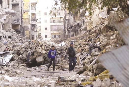 Syrian boys walk amid destroyed buildings in Aleppou2019s formerly rebel-held Al-Shaar neighbourhood yesterday.