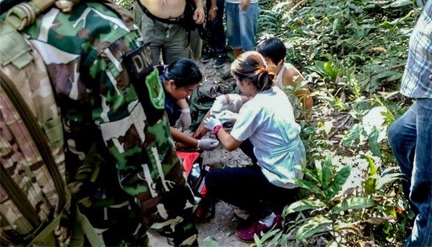 French national Muriel Benetulier (partially obscured) is tended to by medics and park rangers after she was bitten by a crocodile at Thailand's Khao Yai national park.