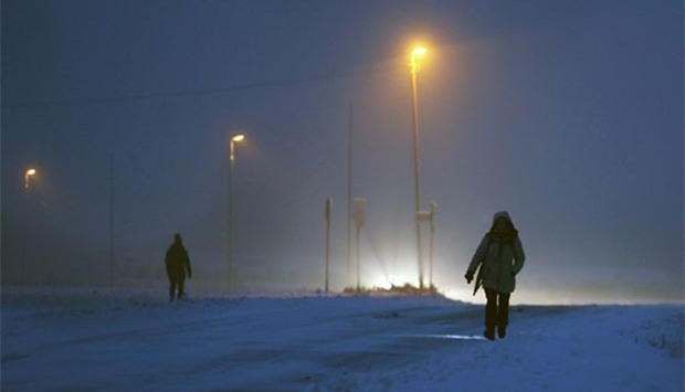 A woman walks through the snow to reach a bus stop in Muelheim, western Germany on Monday.
