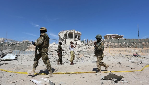 Ugandan soldiers serving in the African Union Mission in Somalia (AMISOM) walk at the scene of an explosion after a suicide attack at a checkpoint outside the main base of an African Union peacekeeping force in the Somali capital Mogadishu