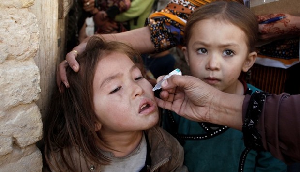 A girl receives polio vaccine drops from an anti-polio vaccination worker outside her family home in Quetta, Pakistan.