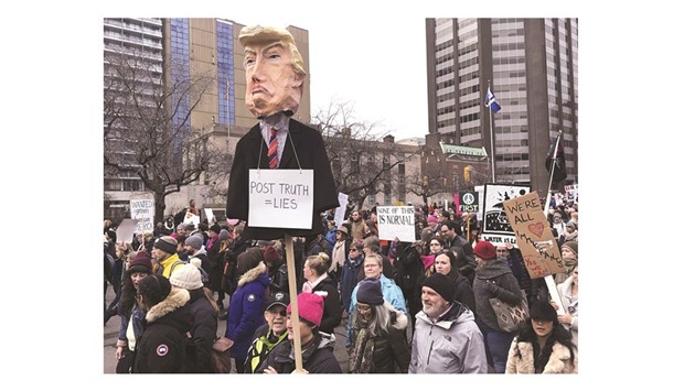 Thousands of people, many wearing pink hats, chant, cheer and hold protest signs while listening to speakers in front of Ontariou2019s provincial legislature, Queenu2019s Park, before marching to the US consulate and Torontou2019s City Hall.