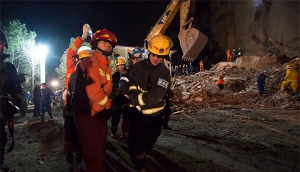 Rescuers carry a trapped person at the site of landslide near a hotel in Xiangyang, Hubei province on Friday.