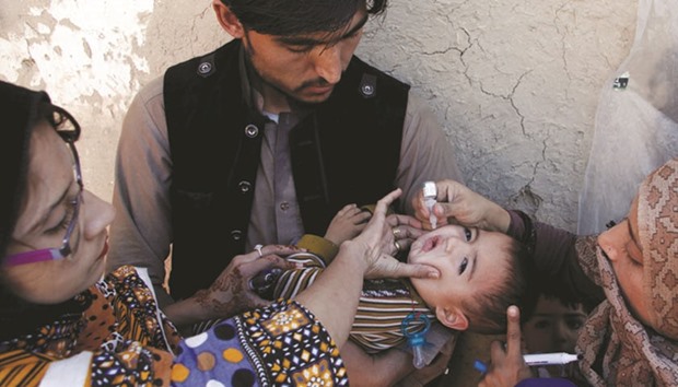 A boy receives polio vaccine drops by anti-polio vaccination workers along a street in Quetta, Pakistan.