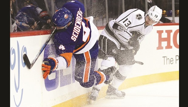 New York Islanders defenseman Dennis Seidenberg (L) is checked into the boards by Los Angeles Kings left wing Kyle Clifford during the third period at Barclays Center.