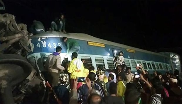 People and rescuers looking for victims from a derailed train in Kuneru, southeast India, early on Sunday.